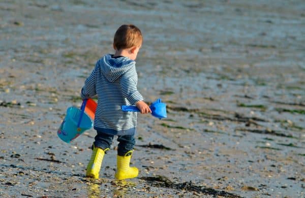 Enfant sur la plage avec pelle et râteau