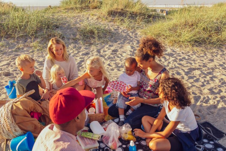 Deux familles avec enfants pique-niquant sur la plage